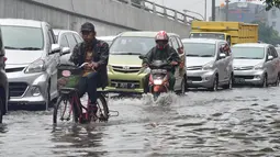 Sejumlah kendaraan memperlambat laju kendaraannya saat melintasi banjir, Minggu (1/2/2015). Hujan deras yang melanda sejak pagi menyebabkan jalan protokol Ibukota di Jalan Pramuka Jakarta, terendam banjir mencapai 20 cm. (Liputan6.com/Andrian M Tunay)