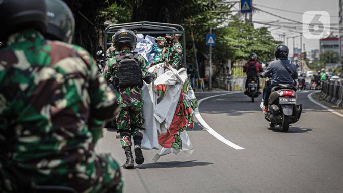 Anggota TNI membawa baliho Rizieq Shihab usai mencopot paksa dari sekitar kawasan Petamburan, Jakarta, Jumat (20/11/2020). Pencopotan dilakukan karena menyalahi aturan yang telah ditetapkan. (Liputan6.com/Faizal Fanani)