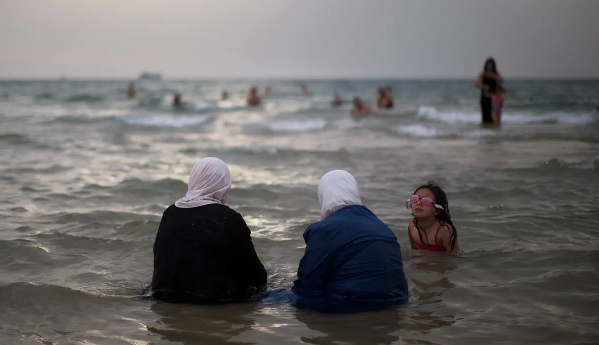 Para ibu warga Palestina berendam di laut saat menghabiskan libur Idul Fitri di pantai Tel Aviv, Israel, Sabtu (16/6). (AP Photo/Oded Balilty)