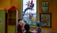 Orang-orang berpakaian seperti “Super Hero” mengantarkan telur Paskah kepada anak-anak yang dirawat di bangsal anak di klinik De Marchi, pada 28 Maret 2024 di Milan, Italia. (Piero Cruciatti/AFP)