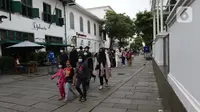 Pengunjung berjalan-jalan di kawasan wisata Kota Tua Jakarta, Minggu (4/4/2021). Libur panjang perayaan Paskah 2021 dimasa pemberlakuan PPKM Berskala mikro dimanfaatkan sejumlah warga untuk berwisata di kawasan Kota Tua Jakarta. (Liputan6.com/Helmi Fithriansyah)