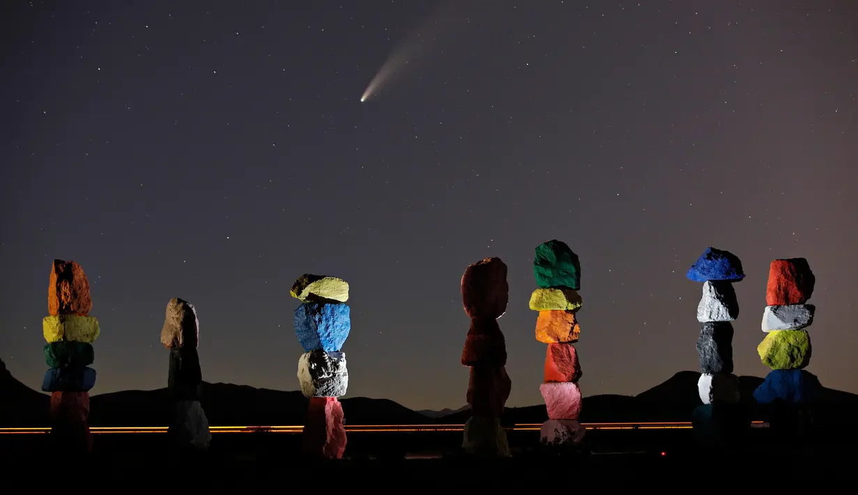 Komet Neowise, atau C / 2020 F3, terlihat di langit malam di atas karya seni berjudul: "Tujuh Magic Mountains" oleh seniman Ugo Rondinone di dekat Jean, Nev., Sebelah selatan Las Vegas, Kamis (16/7/2020). (AP Photo/John Locher)