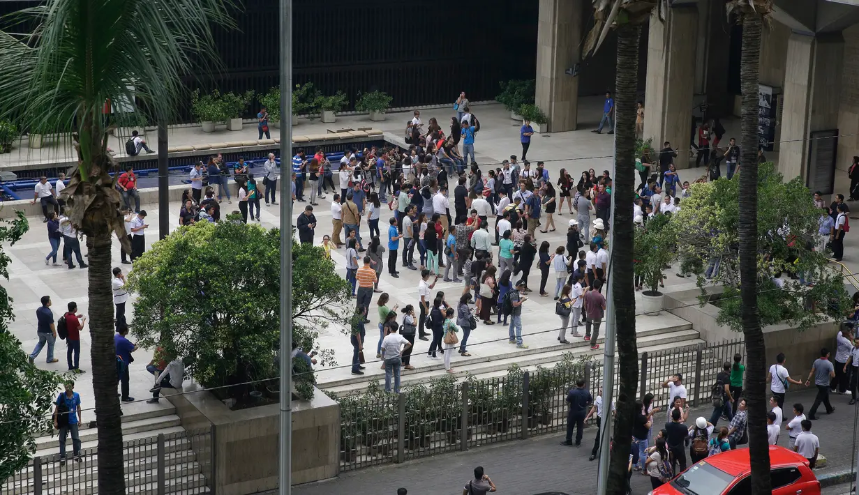Pegawai keluar dari bangunan setelah gempa melanda Manila, Filipina (11/8). Getarannya gempa tersebut terasa hingga ke kereta bawah tanah di Manila. (AP Photo/Aaron Favila)