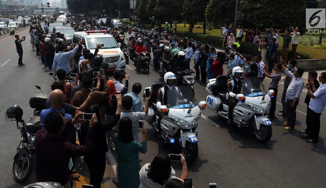 Warga antusias melihat iring-iringan mobil jenazah yang membawa almarhum Presiden ke-3 RI, BJ Habibie saat melintasi Jalan Gatot Subroto menuju TMP Kalibata, Jakarta, Kamis (12/9/2019). BJ Habibie meninggal pada Rabu (11/9/2019) setelah menjalani perawatan di RSPAD. (Liputan6.com/Johan Tallo)