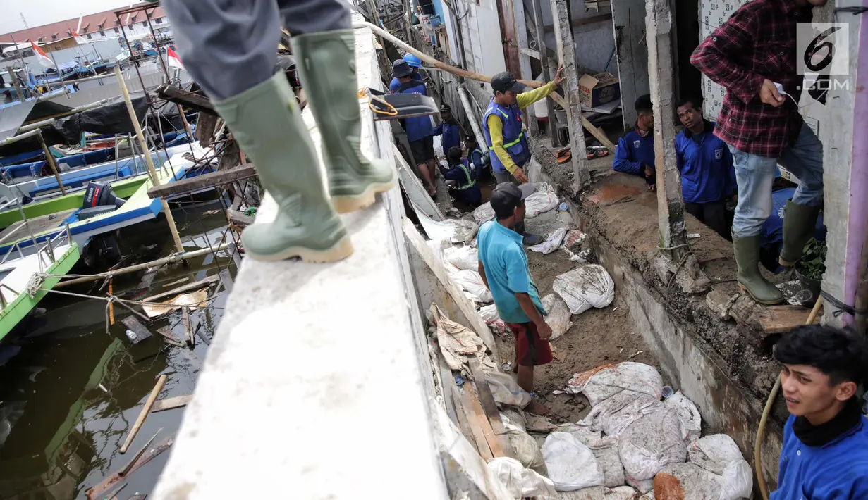 Petugas Sudin Sumber Daya Air Jakarta Utara memperbaiki tanggul jebol di kawasan Luar Batang, Penjaringan, Rabu (8/11). Sekitar 150 orang Pasukan Biru berjibaku memperbaiki tanggul penahan air laut rob yang jebol dua hari lalu (Liputan6.com/Faizal Fanani)