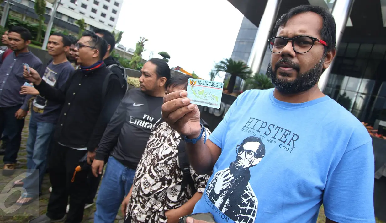 Koordinator KontraS,  Haris Azhar bersama sejumlah orang yang tergabung dalam Koalisi Masyarakat Sipil menunjukan KTP Elektronik saat melakukan aksi di depan Gedung KPK, Jakarta, Minggu (12/3). (Liputan6.com/Immanuel Antonius)