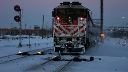 Sebuah kereta komuter melaju menuju pusat kota Chicago ketika api menyala di sepanjang rel di dekat stasiun Metra Western Avenue, 29 Januari 2019. Metra memakai sistem pemanas berbahan bakar gas untuk menghangatkan lintasan yang dingin. (AP/Kiichiro Sato)