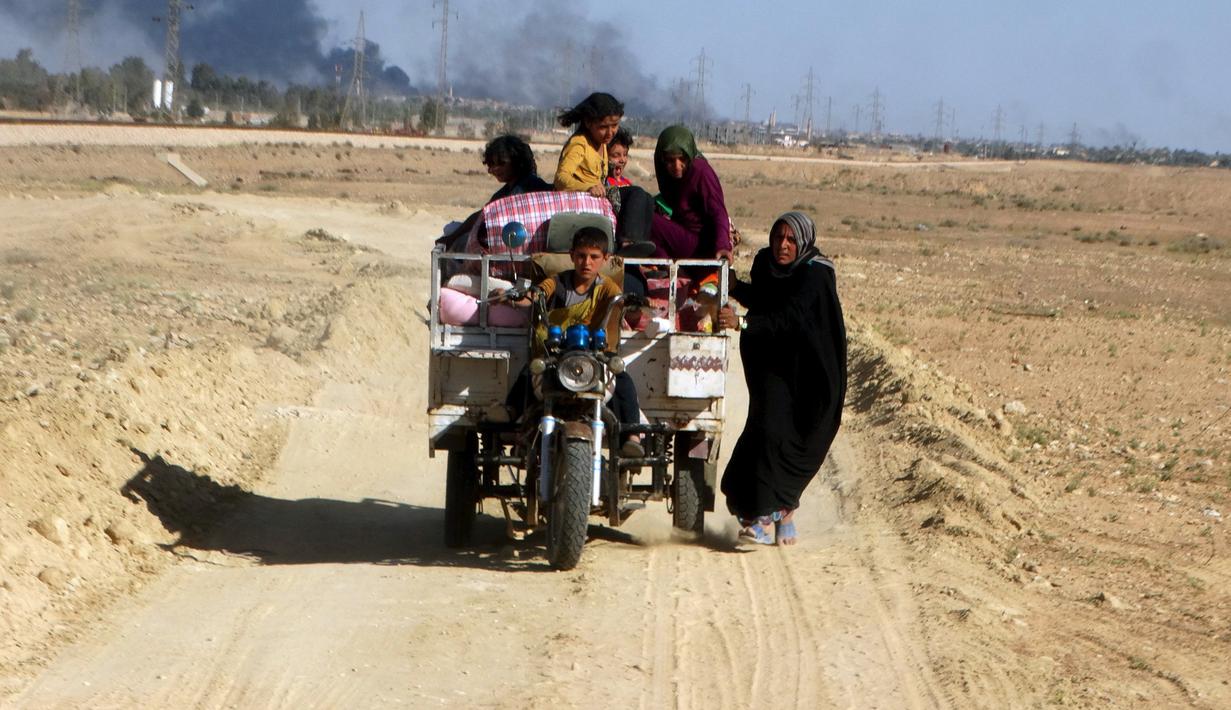 Warga  melarikan diri dari rumah mereka karena bentrokan antara pasukan keamanan Irak dengan militas ISIS di kota Hit, provinsi Anbar, (5/4/2016). (REUTERS/Stringer)