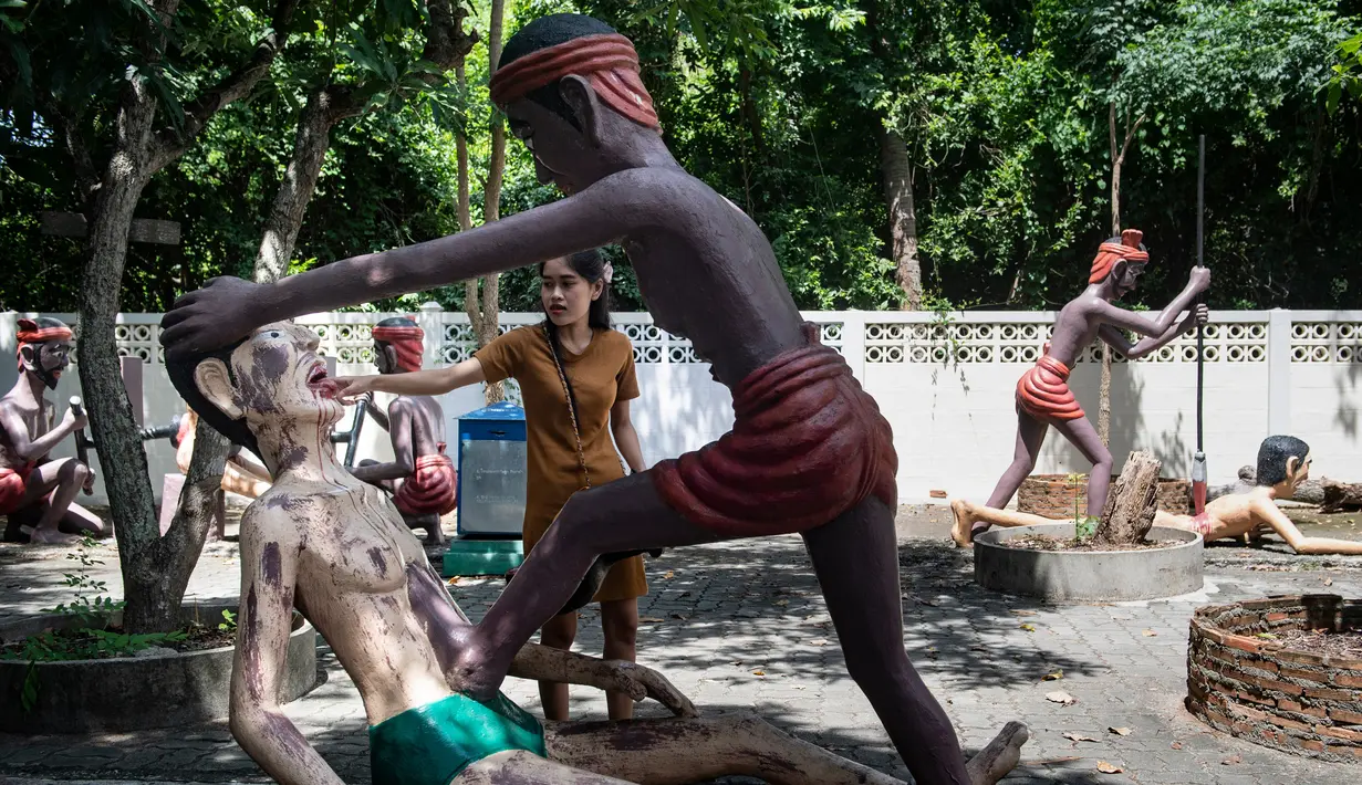 Para pengunjung melihat patung-patung yang menggambarkan nasib orang-orang yang tidak menjunjung tinggi lima ajaran Buddha di sebuah taman yang menggambarkan neraka versi Buddha di kuil Wat Saeng Suk di provinsi pantai Thailand Chonburi (9/7/2020). (AFP/Lillian Suwanrumpha)