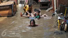Anak-anak bermain di lokasi banjir yang merendam kawasan Kampung Pulo, Jakarta, Selasa (17/11). Kawasan di sepanjang aliran Kali Ciliwung terendam banjir sejak kemarin akibat Bendungan Katulampa yang sudah mencapai siaga satu (Liputan6.com/Gempur M Surya)