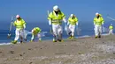 Pekerja dengan pakaian pelindung membersihkan pantai yang terkontaminasi tumpahan minyak di Huntington Beach, California, Amerika Serikat, Selasa (5/10/2021). Kebocoran pipa menyebabkan tumpahan minyak di lepas pantai California. (AP Photo/Ringo H.W. Chiu)
