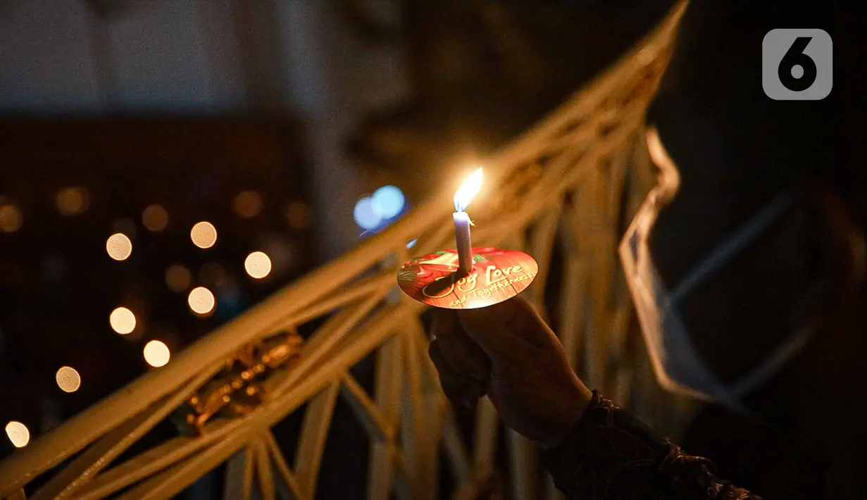 Jemaat memegang lilin saat pelaksanaan ibadah malam Natal di Gereja Immanuel, Jakarta, Jumat (24/12/2021). Perayaan ibadah malam Natal tersebut mengangkat tema 'Cinta Kasih Kristus yang Menggerakkan Persaudaraan'. (Liputan6.com/Faizal Fanani)