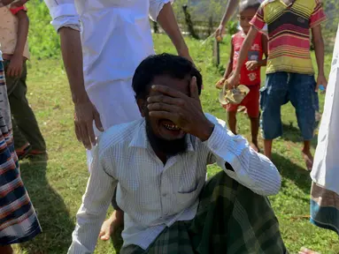 Pengungsi Rohingya Alif Jukhar (tengah) menangis setelah menguburkan kedua orang tuanya yang meninggal saat kapal mereka terbalik untuk menyeberangi Myanmar ke Bangladesh di sebuah pemakaman di Sha Porir Dwip, Teknaf (9/10). (AFP Photo/Munir Uz Zaman)