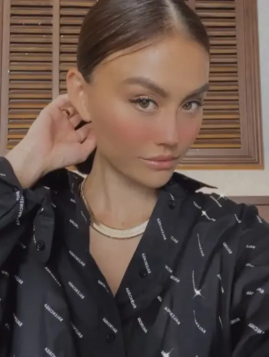 Berpose dengan makeup minimalis, dengan blushon nyebrang hidung. Agnez Mo kenakan kemaja hitam bertuliskan Balenciaga seharga Rp19 jutaan. @agnezmo.