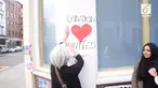 Seorang wanita Inggris dan wanita muslim tampak sedang bersatu memasang sebuah poster dengan tulisan London Heart United.