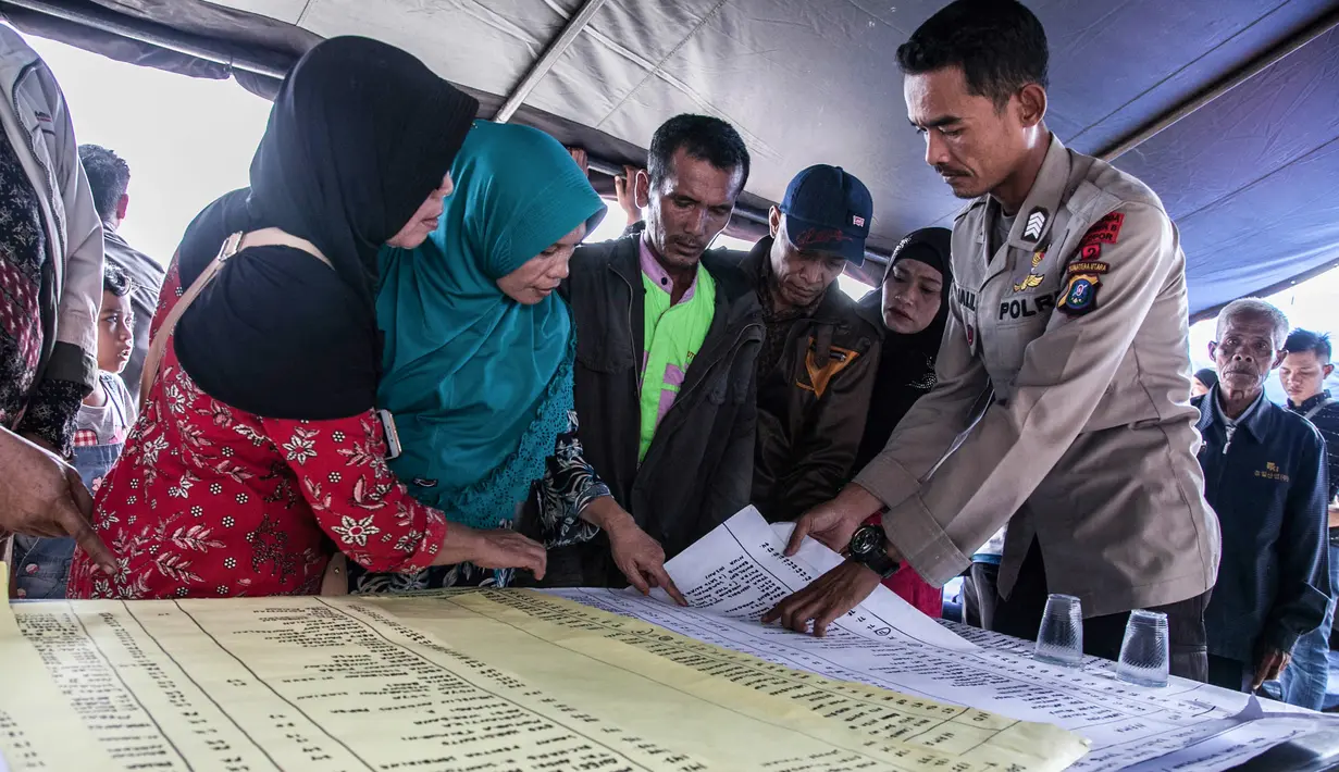 Anggota keluarga melihat daftar nama korban tenggelamnya KM Sinar Bangun di pelabuhan feri Danau Toba, Sumatera Utara, Rabu (20/6). Basarnas menerjunkan 70 personel untuk melakukan pencariankorban tenggelamnya KM Sinar Bangun. (AFP PHOTO/IVAN DAMANIK)