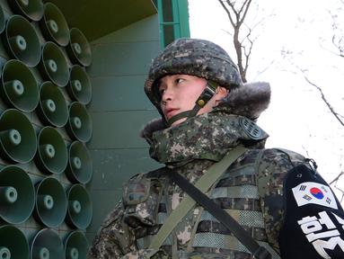 Tentara Korsel berdiri di dekat pengeras suara yang dipasang di sebelah selatan zona demiliterisasi, Yeoncheon, Jumat (8/1/2016). Pengeras suara tersebut memasang musik pop Korea, berita dan kritik atas Korea Utara ke arah perbatasan. (YONHAP/AFP)
