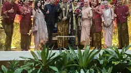Haldy Sabri dan Irish Bella tampak berfoto dengan pasangan pengantin beserta keluarga di pelaminan dalam sesi foto bersama. Irish dan dua anak sambungnya tampak memakai busana senada bernuansa peach dan cokelat muda. (Liputan6.com/IG/@_irishbella_)
