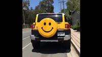 Toyota FJ Cruiser milik diva ini berwarna kuning dengan ban serep bercorak emoticon smile.