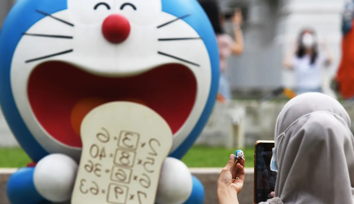 Seorang pengunjung memotret patung Doraemon kecil miliknya berlatarkan salah satu patung di pameran "Doraemon's Time-Travelling Adventures in Singapore" yang digelar di Museum Nasional Singapura pada 3 November 2020. Pameran ini akan berlangsung hingga 27 Desember 2020. (Xinhua/Then Chih Wey)