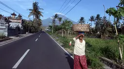 Warga berjalan di sekitar Amed, Kab Karangasem, Bali, Selasa, (26/9). Pusat Vulkanologi dan Mitigasi Bencana Geologis (PVMBG) menaikkan status Gunung Agung dari level III Siaga menjadi level IV Awas, Jumat (22/9) lalu. (AP Photo / Firdia Lisnawati)