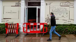 Seorang pria yang mengenakan masker berjalan melewati toko yang baru direnovasi di London, 13 Oktober 2020. Pasar tenaga kerja di Inggris yang terus terpukul akibat dampak pandemi COVID-19 diperkirakan akan membuat lebih banyak orang kehilangan pekerjaan pada musim dingin nanti. (Xinhua/Han Yan)