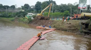 Pekerja Dinas Kebersihan mengangkat sampah kasur yang terjaring disaringan sampah dengan latar belakang alat berat sedang mengeruk lumpur Kali Pesanggrahan, Lebak Bulus, Jakarta Selatan, Rabu (4/11/2020). (merdeka.com/Dwi Narwoko)