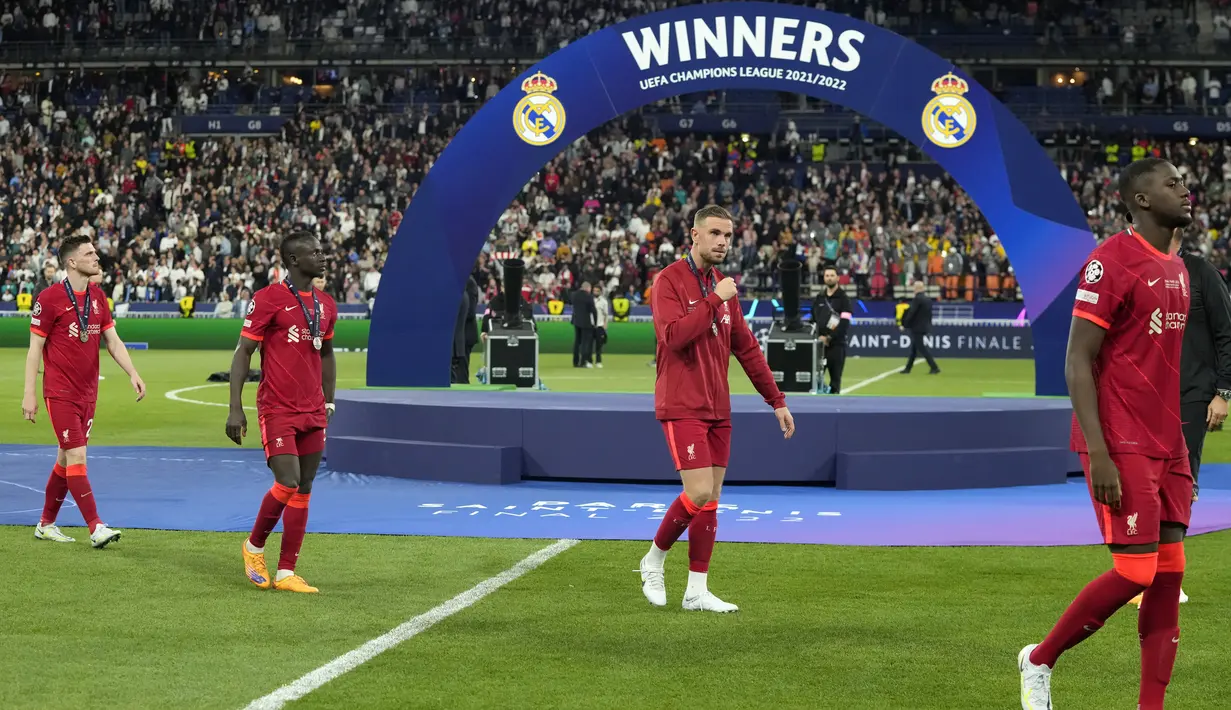 Para pemain Liverpool yang mengenakan medali peringkat kedua berjalan melewati podium pemenang setelah pertandingan sepak bola final Liga Champions antara Liverpool dan Real Madrid di Stade de France, Saint Denis, Prancis, 28 Mei 2022. Real Madrid mengalahkan Liverpool 1-0. (AP Photo/Manu Fernandez)