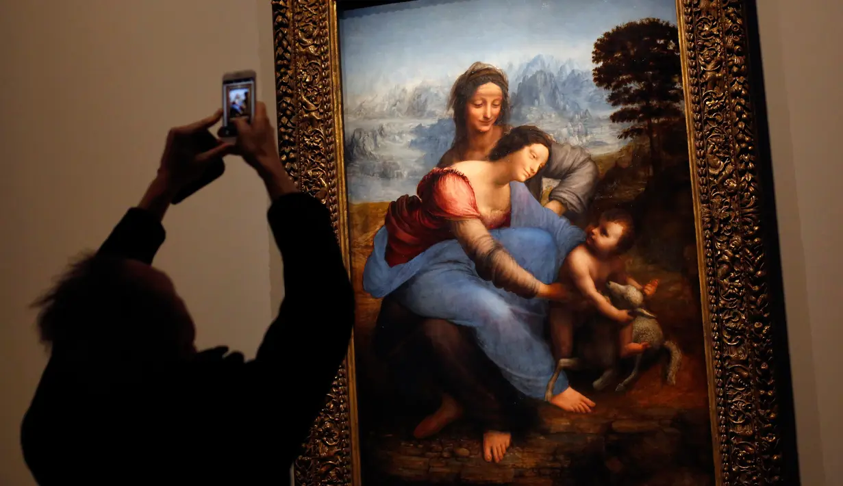 Awak media mengambil gambar "The Virgin and Child with Saint Anne" karya Leonardo Da Vinci di museum Louvre, Paris, Selasa (22/10/2019). Louvre Paris menggelar pameran terbesar  Leonardo da Vinci memperingati 500 tahun wafatnya maestro Italia itu yang dibuka 24 Oktober mendatang (AP/Thibault Camus)