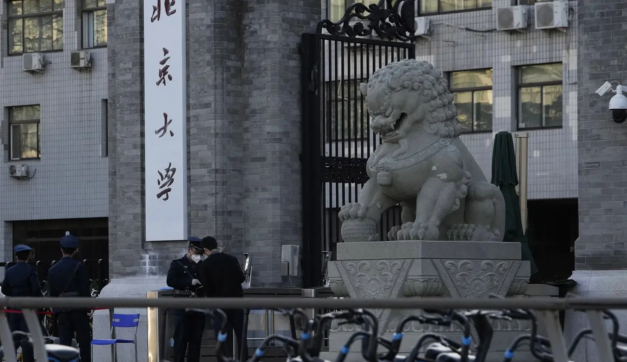 Seorang penjaga keamanan mengobrol dengan yang lain di pintu masuk Universitas Peking di Beijing, Rabu (16/11/2022). Beijing melaporkan lebih dari 350 kasus baru dalam periode 24 jam terakhir, sebagian kecil dari 21 juta populasinya tetapi cukup untuk memicu penguncian dan karantina lokal di bawah strategi "nol-COVID" China.(AP Photo/Ng Han Guan)