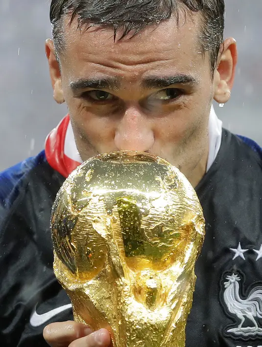 Pemain timnas Prancis, Antoine Griezmann mencium trofi Piala Dunia 2018 saat merayakan gelar juara setelah mengalahkan Kroasia pada  laga final di Luzhniki Stadium, Minggu (15/7). Prancis membekuk Kroasia dengan skor akhir 4-2 (AP Photo/Matthias Schrader)