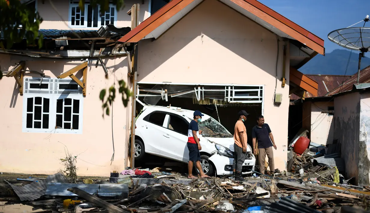 Warga membersihakn rumah mereka setelah gempa bumi dan tsunami menghantam kota Palu, Sulawesi Tengah, Kamis (4/10). BNPB menyebut, hingga Kamis sore, jumlah korban meninggal akibat gempa dan tsunami Palu mencapai 1.558 orang. (AFP/Jewel SAMAD)