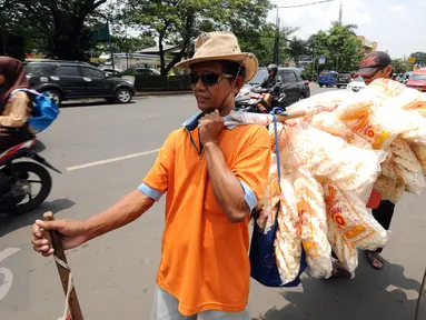 Iman (depan) bersama Drajat berjalan menjajakan kerupuk ikan di Jalan Raya Bogor, Depok, Jawa Barat, Rabu (19/10). Iman mengaku setiap harinya berjalan kaki menyusuri Jalan Raya Bogor untuk menjajakan dagangannya. (Liputan6.com/Helmi Fithriansyah)