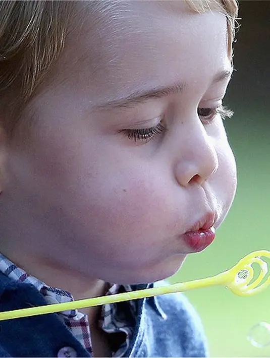 George sangat menikmati momen bermain gelembung sabun itu, tanpa disadarinya, kamera menangkap ekspresi lucunya yang menggembungkan pipi dengan bibir mungil merahnya. (doc.people.com)