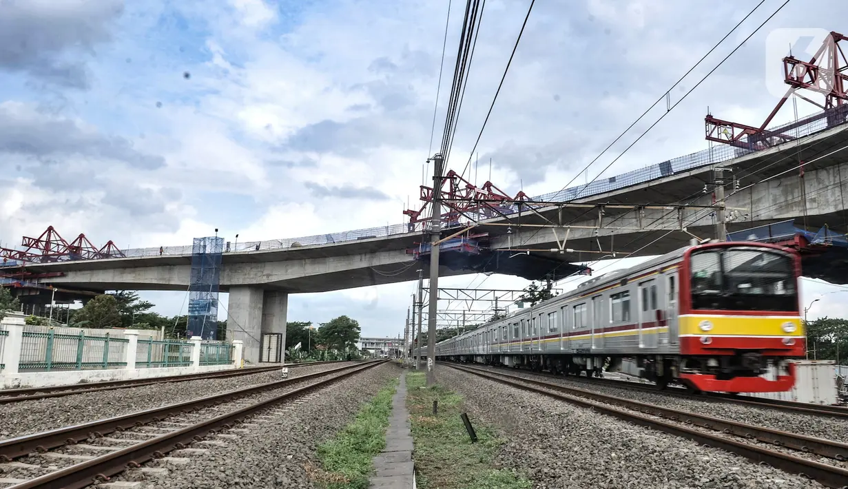 Kereta Commuter Line melintas di bawah proyek pembangunan jalur lintas atas (flyover) Cakung, Jakarta, Kamis (17/12/2020). Proyek Flyover Cakung saat ini telah mencapai 94 persen dan sedang menyelesaikan pemasangan balok girder pada bentang yang melintasi rel kereta api. (merdeka.com/Iqbal Nugroho)