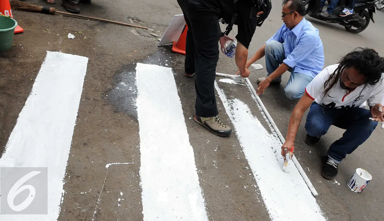Para Aktivis Pejalan Kaki mengecat marka jalan  di kawasan Tosari, Jakarta, Jumat (11/12). Mereka mengajak masyarakat agar sadar untuk berlalu lintas jalan yang aman dan selamat. (Liputan6.com/Helmi Afandi)