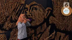 Pengunjung berswafoto di depan karya instalasi bambu berbentuk wajah Jenderal Sudirman karya Nus Salomo yang dipamerkan pada aksi Kenali Sejarah Raihlah Mimpimu di Terowongan Dukuh Atas, Jakarta, Minggu (24/11/2019). (Liputan6.com/Johan Tallo)