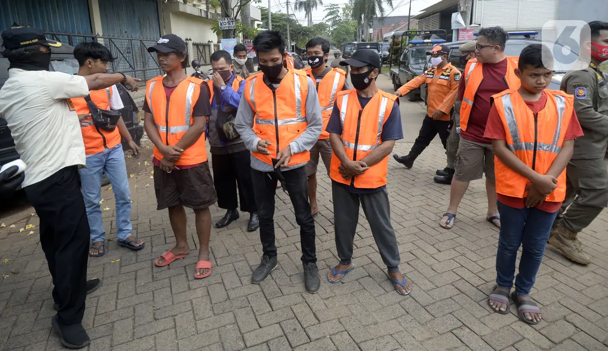 Petugas menghukum warga pelanggar PSBB yang terjaring Operasi Yustisi di BSD, Tangerang Selatan, Banten, Rabu (16/9/2020). Sanksi sosial lari sejauh 800 meter diberikan kepada warga pelanggar PSBB untuk memberikan efek jera. (merdeka.com/Dwi Narwoko)