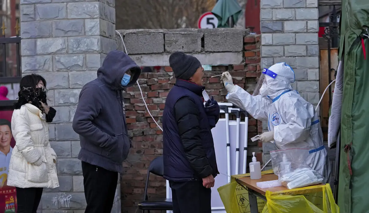 Seorang pekerja medis yang mengenakan alat pelindung diri melakukan tes COVID-19 kepada warga di Distrik Fengtai, Beijing, China, Rabu (26/1/2022). Jelang Olimpiade Musim Dingin, Beijing melaporkan peningkatan lebih dari selusin kasus baru COVID-19 setiap harinya. (AP Photo/Andy Wong)