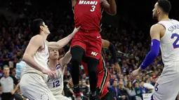 Pemain Miami Heat, Dwyane Wade melakukan tembakan melewati adangan para pemain Philadelphia 76ers pada NBA basketball playoff series di Wells Fargo Center, Philadelphia, (16/4/2018). Heat menang 113-103. (AP/Chris Szagola)