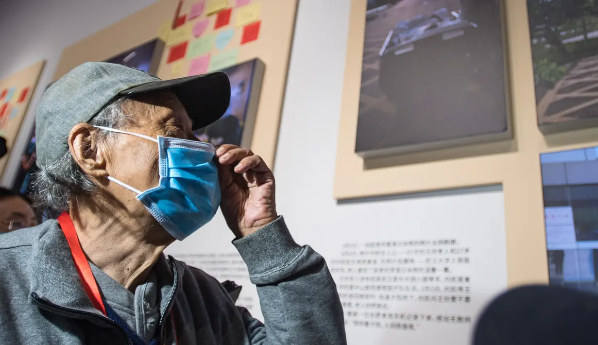 Wang Xin, warga yang sembuh dari COVID-19, melihat foto dirinya menikmati matahari terbenam saat masih menjadi pasien bersama seorang staf medis, yang menjadi viral di internet, dalam pameran perjuangan China melawan epidemi COVID-19 di Wuhan, Provinsi Hubei, China (15/10/2020). (Xinhua/Xiao Yijiu)