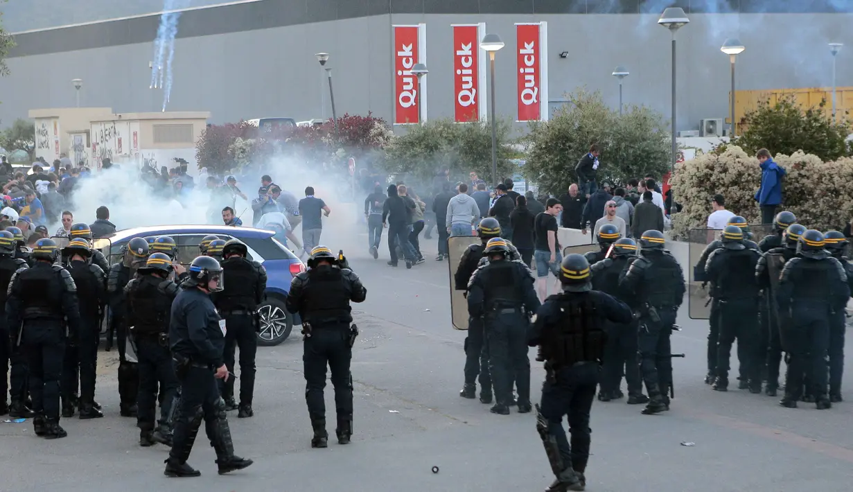 Polisi anti rusuh Prancis menghalau  suporter Bastia dengan gas air mata saat laga SC Bastia melawan Olympic Lyon di Armand Cesari stadium, Bastia, (16/4/2017). Laga ini akhirnya dihentikan LFP. (AFP/Pascal Pochard-Casabianca)