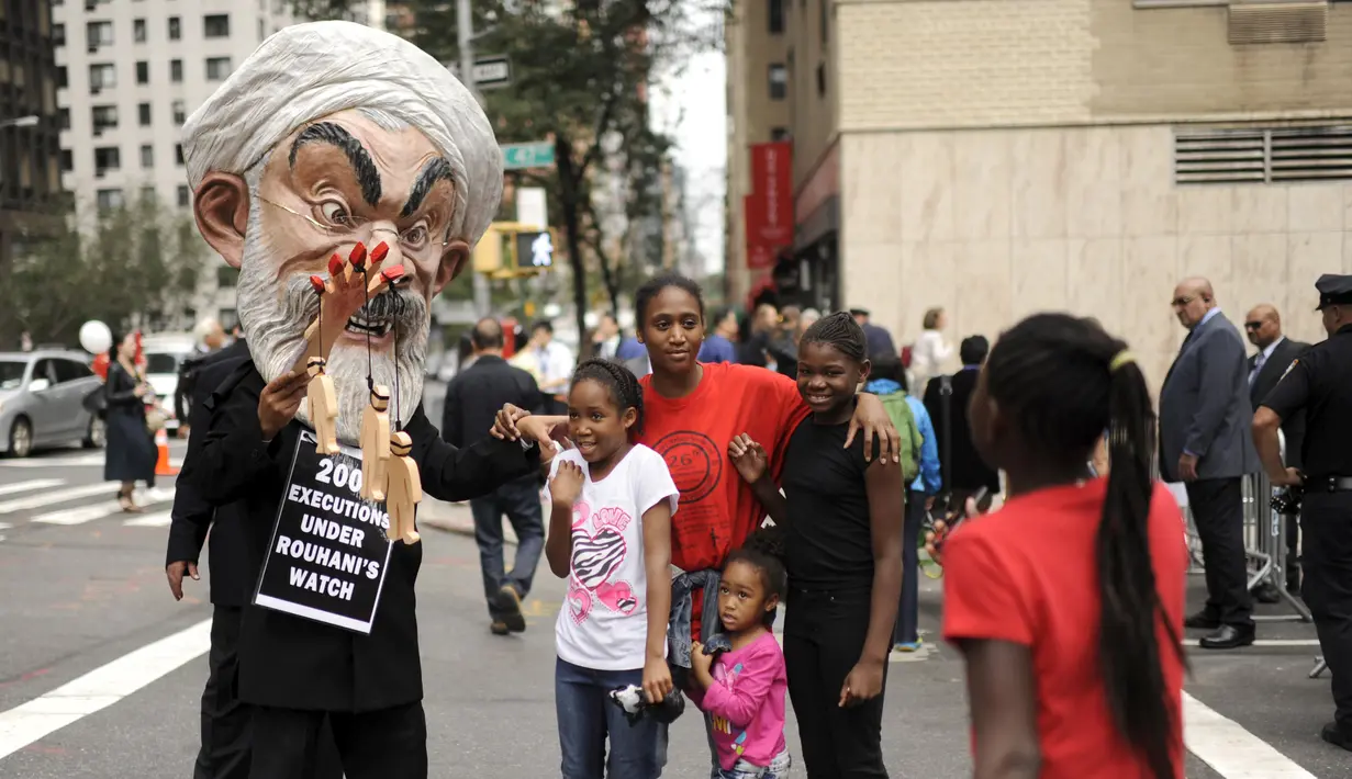 Warga berselfie dengan Max Saatchi yang memakai topeng Presiden Iran Hassan Rouhani saat unjuk rasa mengecam pelanggaran hak asasi manusia oleh pemerintah Rouhani di luar markas besar PBB, Manhattan, New York, AS (28/9/2015). (REUTERS/Darren Ornitz)