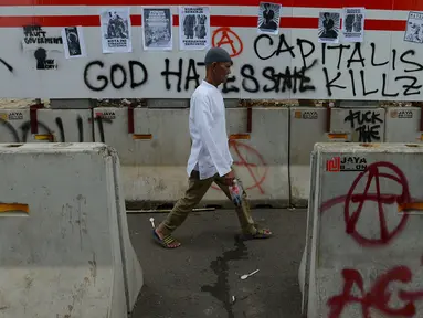 Pejalan kaki melintas dekat aksi vandalisme yang mewarnai Hari Buruh Internasional atau May Day di kawasan Bundaran HI, Jakarta, Rabu (1/5/2019). Belum diketahui siapa yang melakukan aksi corat coret di fasilitas publik tersebut. (merdeka.com/Imam Buhori)