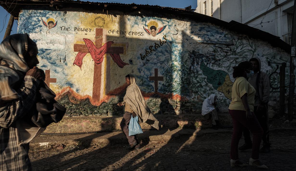Orang-orang melintas di sebuah jalan di Kota Gondar, Ethiopia pada 09 November 2020. (Photo by EDUARDO SOTERAS / AFP)