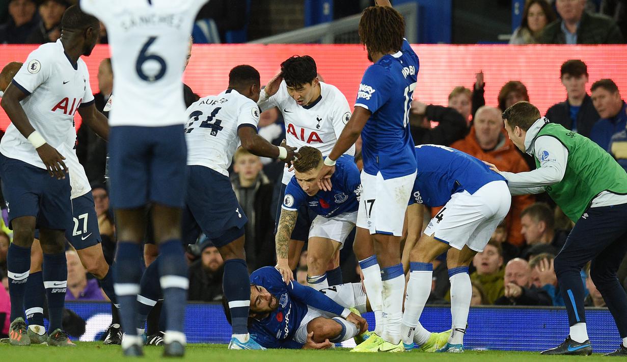 Penyerang Tottenham Hotspur, Son Heung-min, tampak menyesal usai melakukan pelanggaran terhadap gelandang Everton, Andre Gomes, pada laga Premier League di Goodison Park, Minggu (3/11). Tekel tersebut menyebabkan Gomes mengalami patah kaki. (AFP/Oli Scarff)