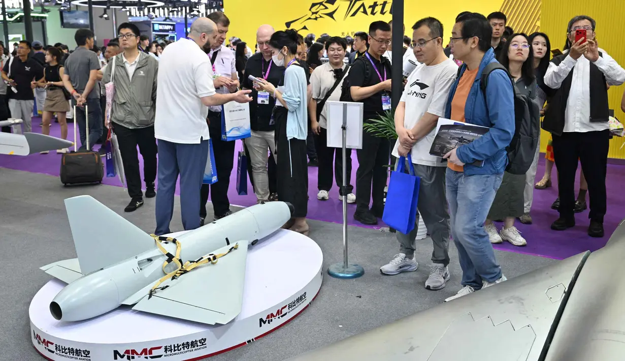 Pengunjung terlihat berdiri di samping model drone UAV Winged Tiger H1500 di stan Micro Multi Copter (MMC) selama Drone World Congress (DWC) di Shenzhen pada 21 Mei 2026. (HECTOR RETAMAL/AFP)