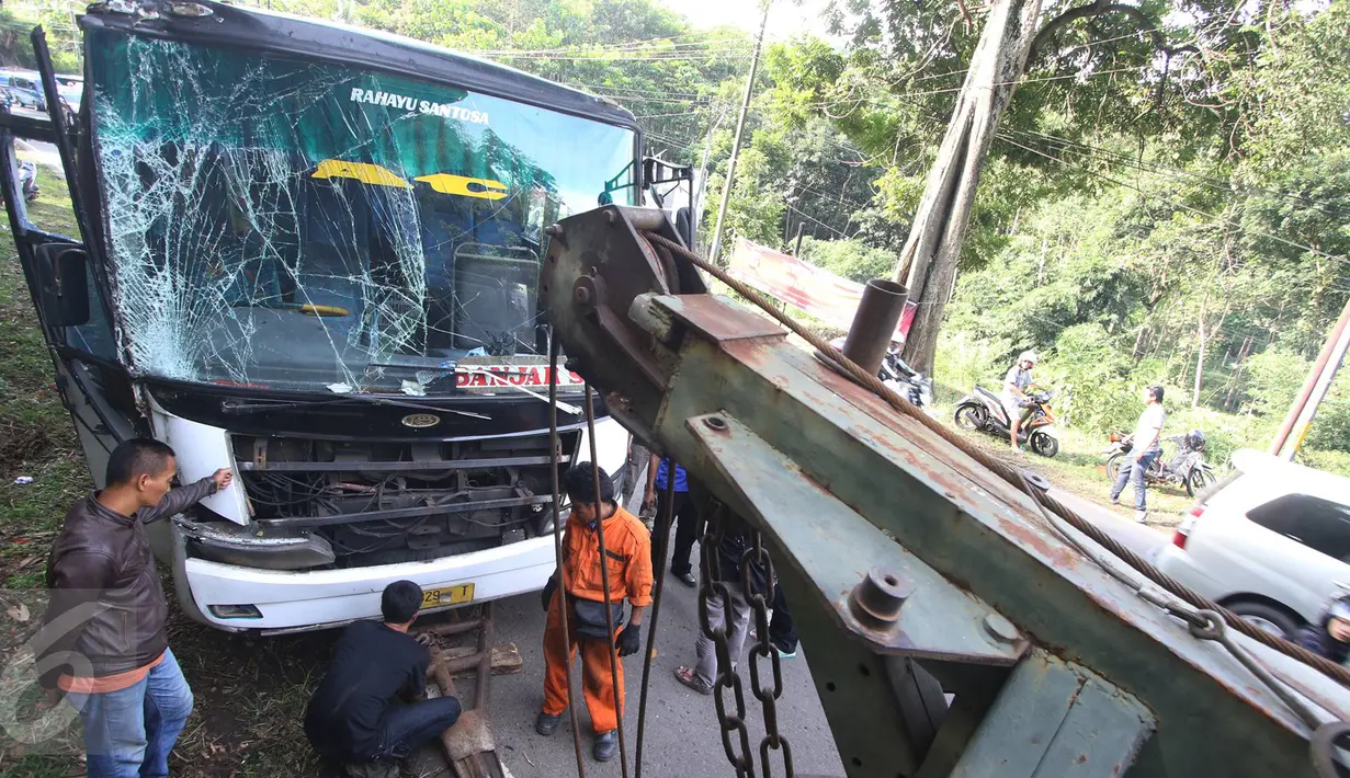 Petugas menggunakan mobil derek untuk mengevakuasi bus PO Merdeka yang menabrak pohon di jalur Lingkar, Jawa Barat, Sabtu (2/7). Kecelakaan terjadi karena rem bus bernopol Z 7829 T itu tidak berfungsi, alias blong. (Liputan6.com/Immanuel Antonius)