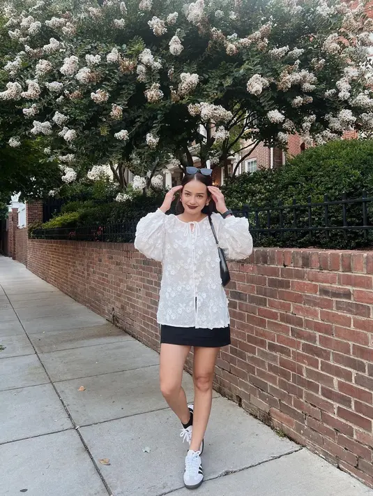 Tak lama, Enzy Storia dan Molen Kasetra Kembali ke Amerika, karena Molen masih bertugas sebagai diplomat di sana. Melihat gaya manis Enzy dengan atasan blouse putih dengan bordir floral dan rok mini hitam. [Foto: Instagram/enzystoria]