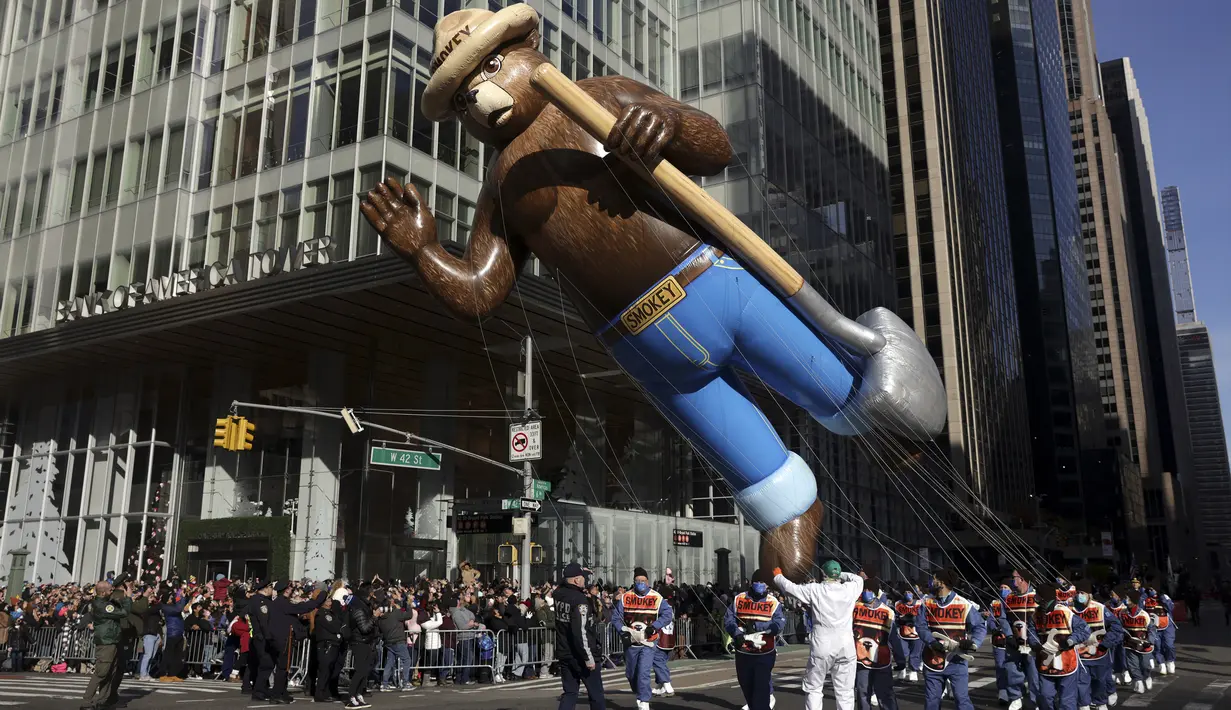 Pawang balon menarik Smokey the Bear melalui persimpangan Sixth Avenue dan 42nd Street pada Macy's Thanksgiving Day Parade di New York, Amerika Serikat, 25 November 2021. Macy's Thanksgiving Day Parade kembali sepenuhnya setelah dirundung pandemi COVID-19 tahun lalu. (AP Photo/Jeenah Moon)